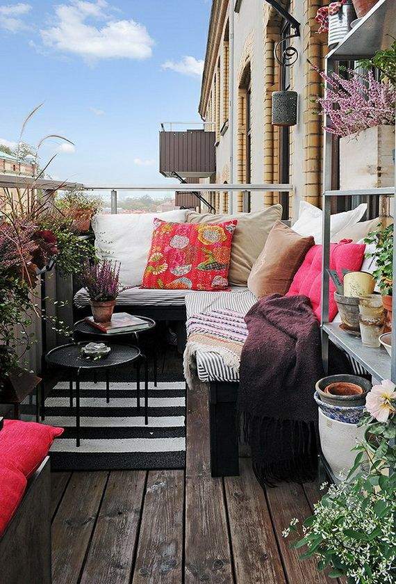 Varanda decorada com plantas, móveis confortáveis e almofadas coloridas.